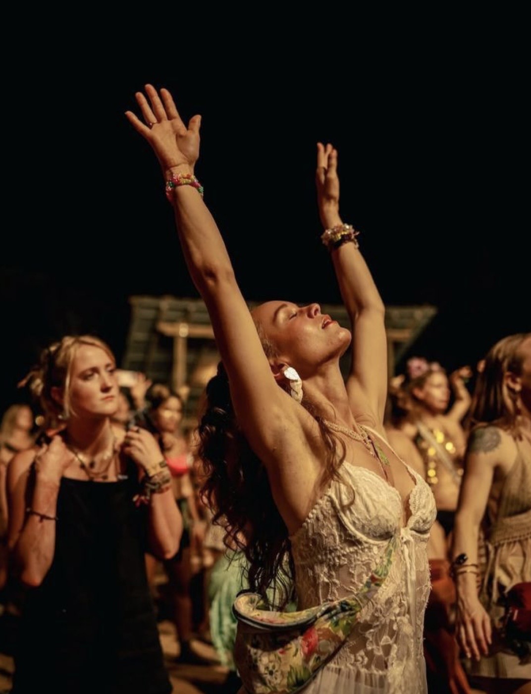 Dancer with arms raised under starlit night sky