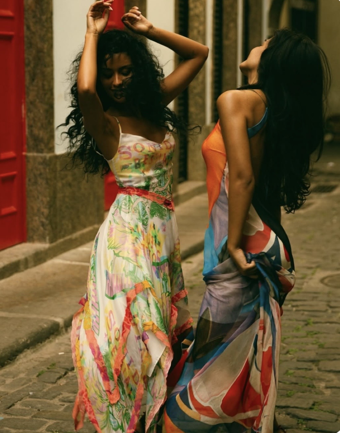 Two dancers in colorful dresses on a cobblestone street