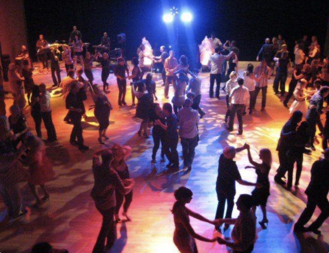 Crowded social dance floor with stage lights
