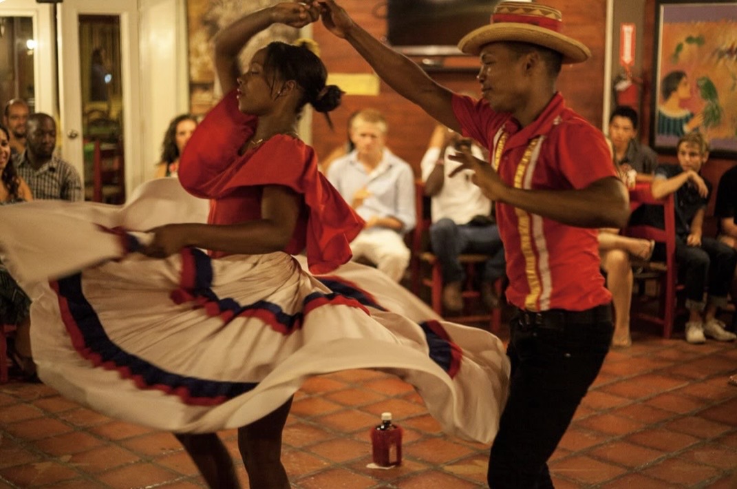 Couple performing traditional Caribbean dance in red attire